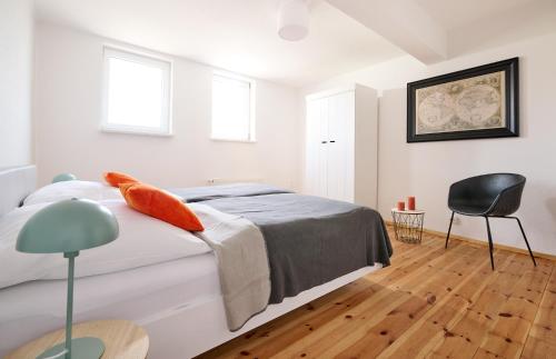 a white bedroom with a bed and a chair at Ferienwohnung im Leipziger Neuseenland in Böhlen