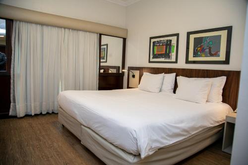 a large white bed in a hotel room at Plaza Blumenau Hotel in Blumenau