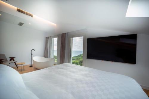 a white bedroom with a large bed and a large window at Hotel Boutique Berazadi Berri in Zarautz