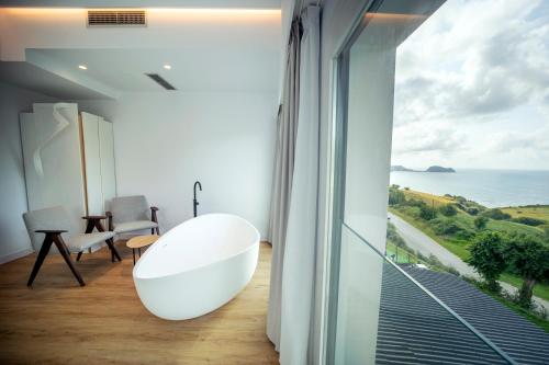 a bathroom with a large white tub and a view of the ocean at Hotel Boutique Berazadi Berri in Zarautz