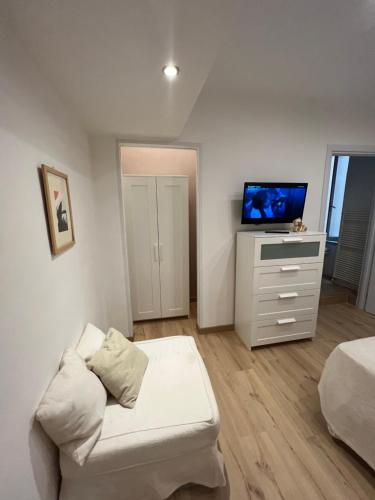 a white living room with a couch and a tv at Alla Scalinata del Teatro Rossetti confort suites parcheggio in Trieste