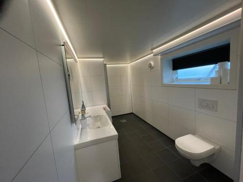 uma casa de banho com um WC, um lavatório e uma janela em Leilighet med havutsikt 