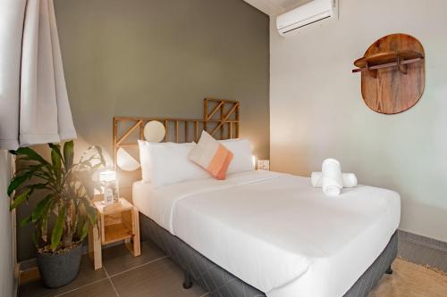 a bedroom with a white bed and a plant at Selina River Venao in Playa Venao