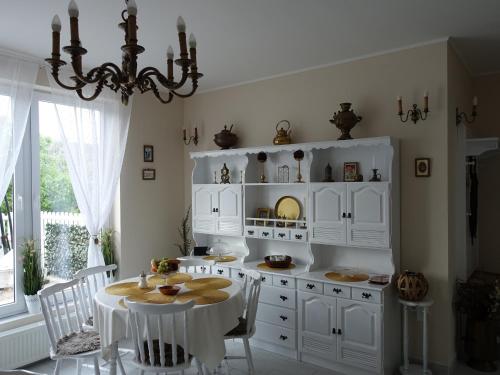 cocina blanca con mesa y lámpara de araña en Wagner Apartman Tata, en Tata