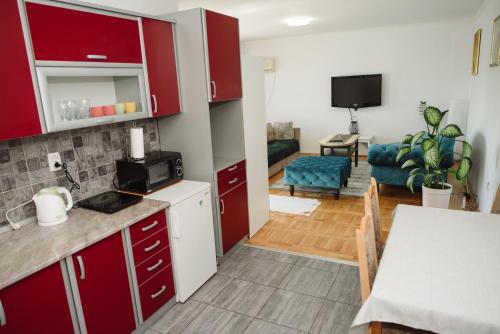 cocina con armarios rojos y sala de estar. en Apartman Star en Subotica