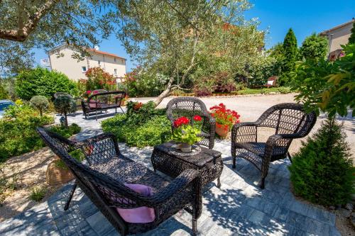un patio con sillas y una mesa con flores en Apartment Skaline en Malinska