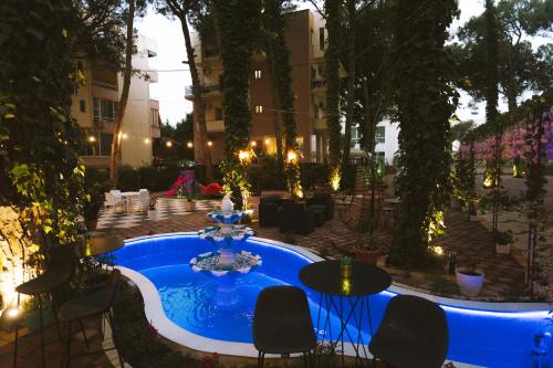 a pool with chairs and a table and a fountain at Hotel Mali i Robit in Golem