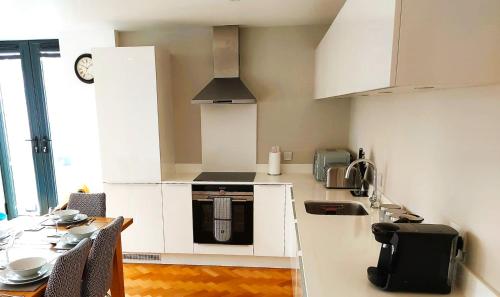 a kitchen with white cabinets and a table with chairs at Beautiful Apartment In The Heart of Chelmsford in Chelmsford