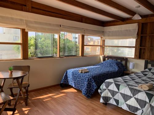 a bedroom with two beds and a table and windows at Apartamento en zona monumental de Barranco in Lima