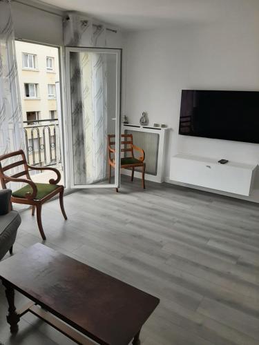 sala de estar con TV de pantalla plana en la pared en Appartement cosy de centre ville, en Charenton-le-Pont