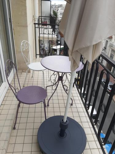 uma mesa e cadeiras numa varanda com um guarda-sol em Appartement cosy de centre ville em Charenton-le-Pont