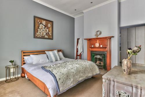 a bedroom with a large bed and a fireplace at SASHORES- 6 on Ellis in Cape Town