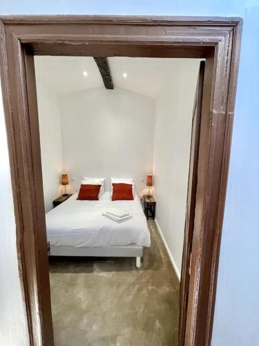 ein Schlafzimmer mit einem weißen Bett mit zwei roten Kissen in der Unterkunft NEW, La Passante, Belle vue in Conques-sur-Orbiel