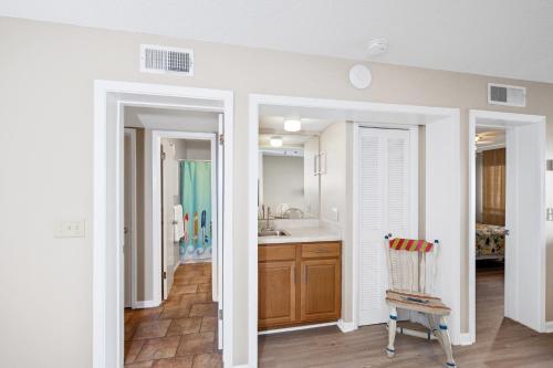 a kitchen with white walls and wooden cabinets at A Wave From it All Beach Resort in Gulf Shores