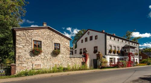 a stone building next to a white building with flower boxes at BioRezydencja in Świeradów-Zdrój