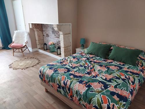 a bedroom with a bed with a colorful comforter and a fireplace at Sous murs, petite maison de ville au charme authentique in Auxerre