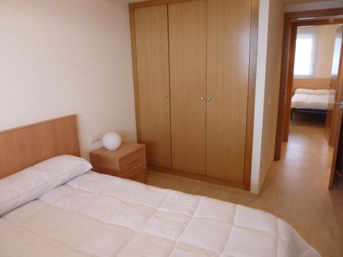1 dormitorio con cama blanca y armario de madera en Apartamentos Deluxe Peñíscola, en Peñíscola