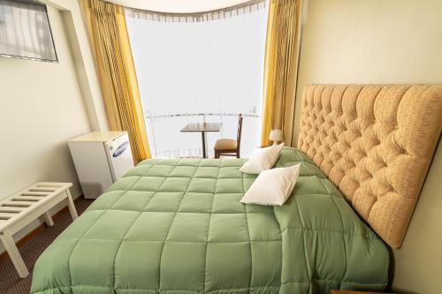 - une chambre avec un lit vert et une grande fenêtre dans l'établissement Hotel San Felipe Suites, à Arequipa