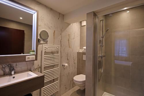y baño con ducha, aseo y lavamanos. en Hotel Uilenspiegel, en Nieuwpoort