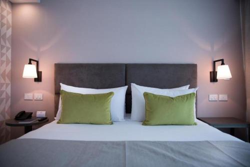 1 dormitorio con 1 cama grande con almohadas verdes en Howard Johnson Plaza Buenos Aires en Buenos Aires