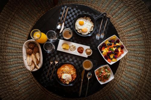 サンタ・テレサにあるLALOON Luxury Suites - Adults Onlyの朝食の食べ物と飲み物の皿が置かれたテーブル
