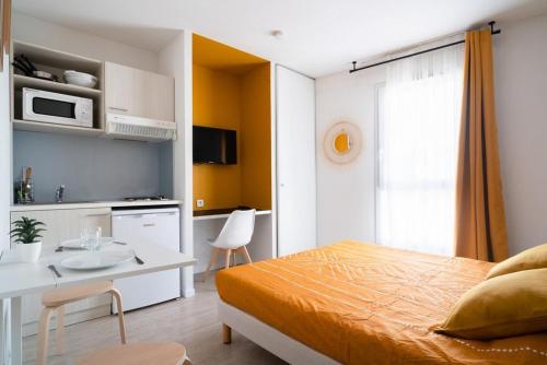 een slaapkamer met een bed en een tafel en een keuken bij Joli studio proche gare et centre ville in Lourdes