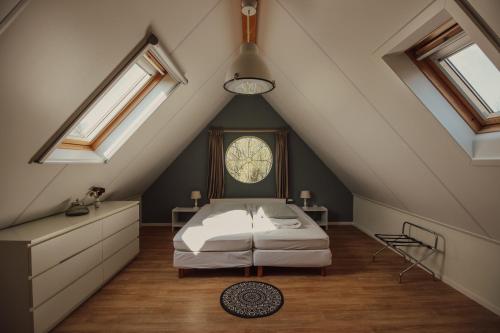a attic bedroom with a bed and skylights at de Kafzolder in Retranchement