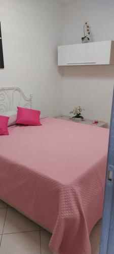uma cama cor-de-rosa com um cobertor cor-de-rosa em APPARTAMENTO IN SOTTOMARINA DI CHIOGGIA em Chioggia