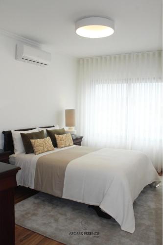 a white bedroom with a large bed and a window at Azores Essence - Paim in Ponta Delgada