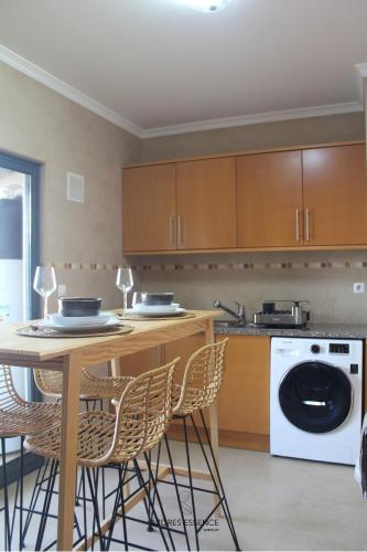 a kitchen with a table and chairs and a dishwasher at Azores Essence - Paim in Ponta Delgada