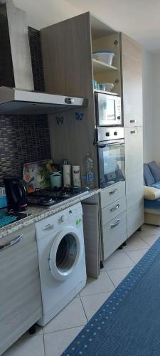 uma cozinha com uma máquina de lavar roupa e um micro-ondas em APPARTAMENTO IN SOTTOMARINA DI CHIOGGIA em Chioggia