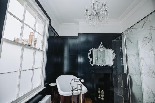 a bathroom with black walls and a chandelier at Stunning 5 bedroom period property by the sea in Kent