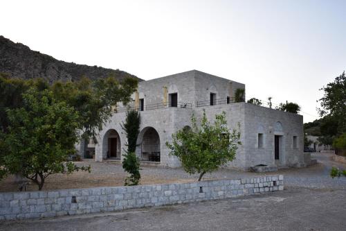 una antigua casa de piedra con una pared de piedra en Akroyiali Apartments, en Yerolimin