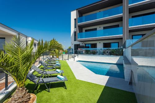 a row of lounge chairs next to a building with a swimming pool at PS Apartments in Pula