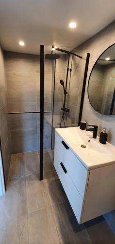 La salle de bains est pourvue d'un lavabo blanc et d'une douche. dans l'établissement Studio terrasse Indépendante Vue Exceptionnelle, à Sète