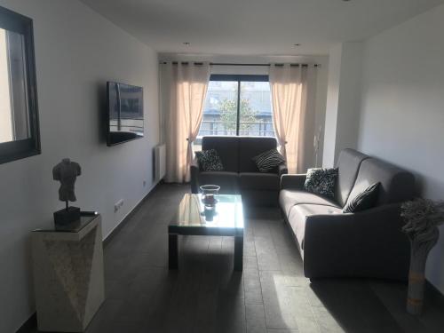 a living room with a couch and a table at Aux Grès des Vagues in Lion-sur-Mer