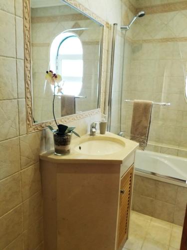 a bathroom with a sink and a mirror and a tub at Casa Bonequinha in Nazaré