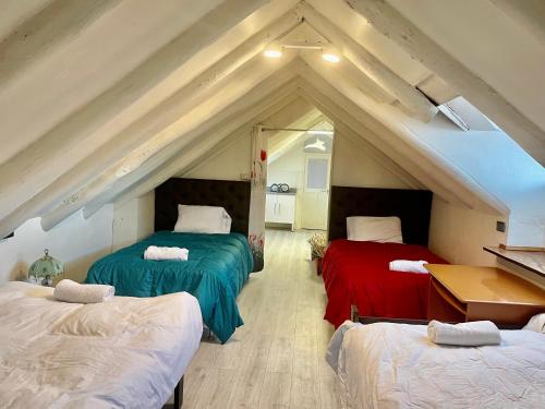 um quarto no sótão com 3 camas e uma mesa em Sight Qoricancha em Cusco