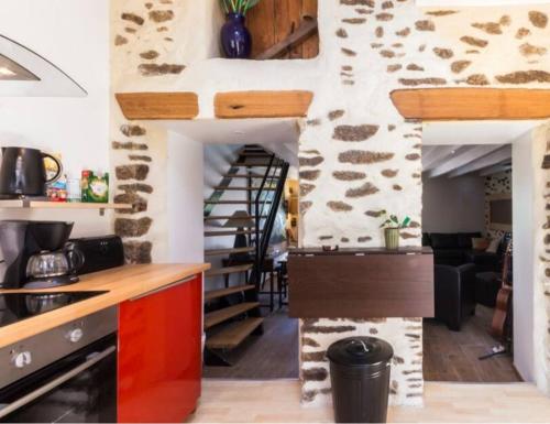 uma cozinha com uma parede de pedra e uma escada em espiral em Gite Kerlaguito em Pontchâteau