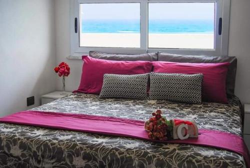 1 dormitorio con 1 cama grande con sábanas rosas y ventana en CRISVAN HOME, en Isola di Capo Rizzuto