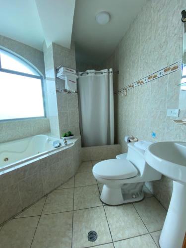 a bathroom with a toilet and a tub and a sink at Hotel Cumbayá Sanvy in Quito