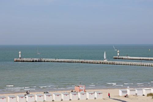 a beach with a pier with a boat in the water at Hotel Uilenspiegel in Nieuwpoort