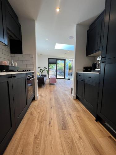 a kitchen with black cabinets and a wooden floor at Modern Studio with parking in private garden in Theydon Bois