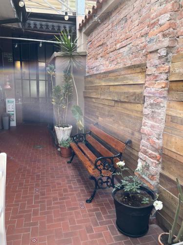 a bench sitting next to a brick wall with potted plants at Ferienhaus Hostel Salta in Salta