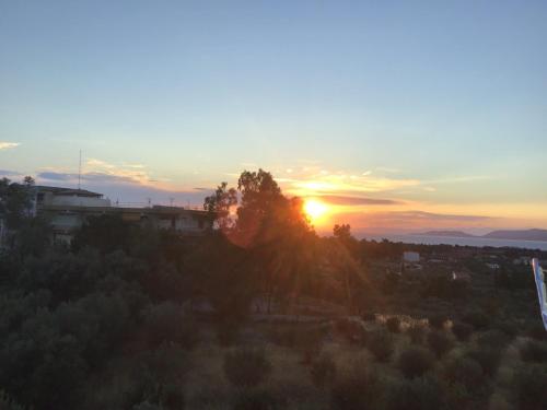 a sunset over a city with the sun setting at Loutraki Getaway - Cozy and Quiet Nest in Loutraki