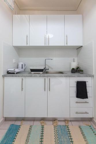 a kitchen with white cabinets and a sink at Loutraki Getaway - Cozy and Quiet Nest in Loutraki