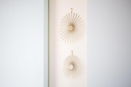 two metal sunburst earrings hanging on a white wall at Loutraki Getaway - Cozy and Quiet Nest in Loutraki