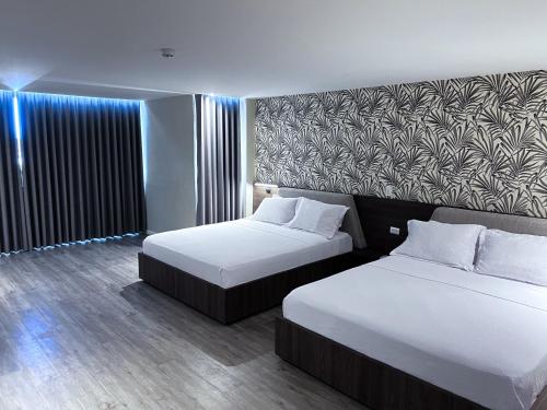 a hotel room with two beds and a wall at Eslait Hotel & Apartamentos in Barranquilla