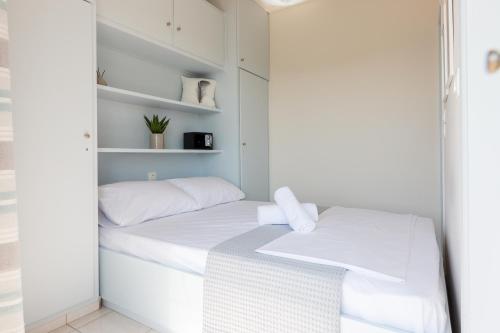a small bedroom with a white bed and shelves at Loutraki Getaway - Cozy and Quiet Nest in Loutraki