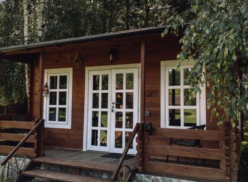 drewniany domek z białymi oknami i werandą w obiekcie Laumių Nameliai w mieście Onikszty
